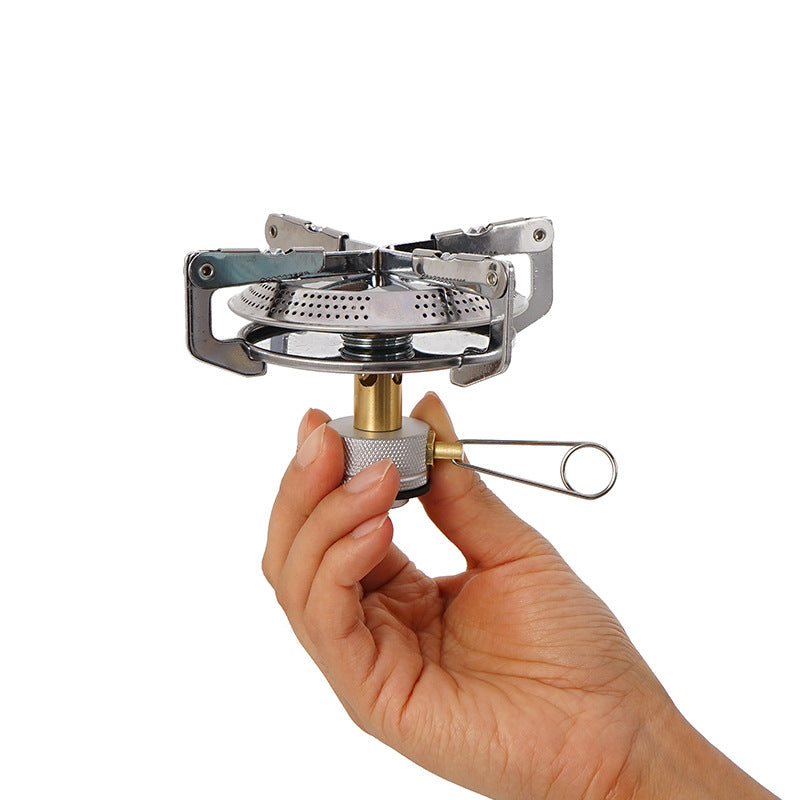 A man holds the upper part of the Portable Windproof Camping Gas Stove on a white surface
